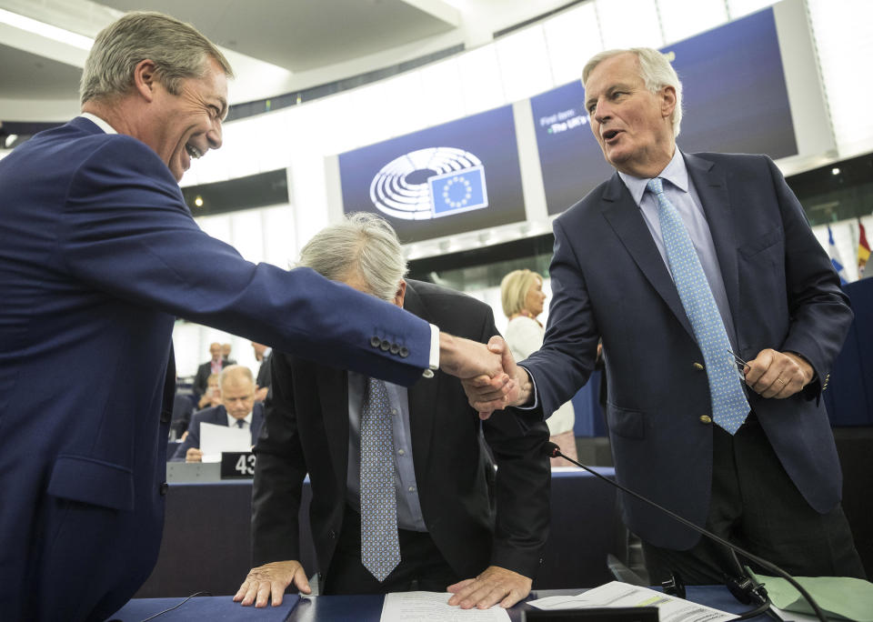 Brexit Party leader Nigel Farage, left, shakes hands with European Union chief Brexit negotiator Michel Barnier while European Commission President Jean-Claude Juncker leans forward Wednesday, Sept. 18, 2019 in Strasbourg. Members of the European Parliament discuss the current state of play of the UK's withdrawal from the EU. (AP Photo/Jean-Francois Badias)