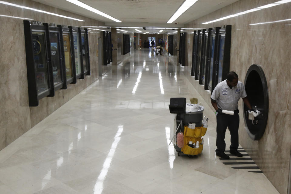 Custodian Anton Jennings cleans one of the water fountains on the first floor hallway of the state Capitol in Sacramento, Calif., Wednesday, March 18, 2020. In a precautionary effort to deal with the coronavirus, the Capitol and Legislative Office Building were closed to the public with only essential state workers and legislative employees allowed in until further notice, based on a "stay at home" directive issued by Sacramento County. (AP Photo/Rich Pedroncelli)
