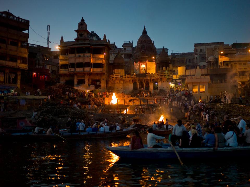 Tourists watch funeral pyres burn at Varanasi in 2011.