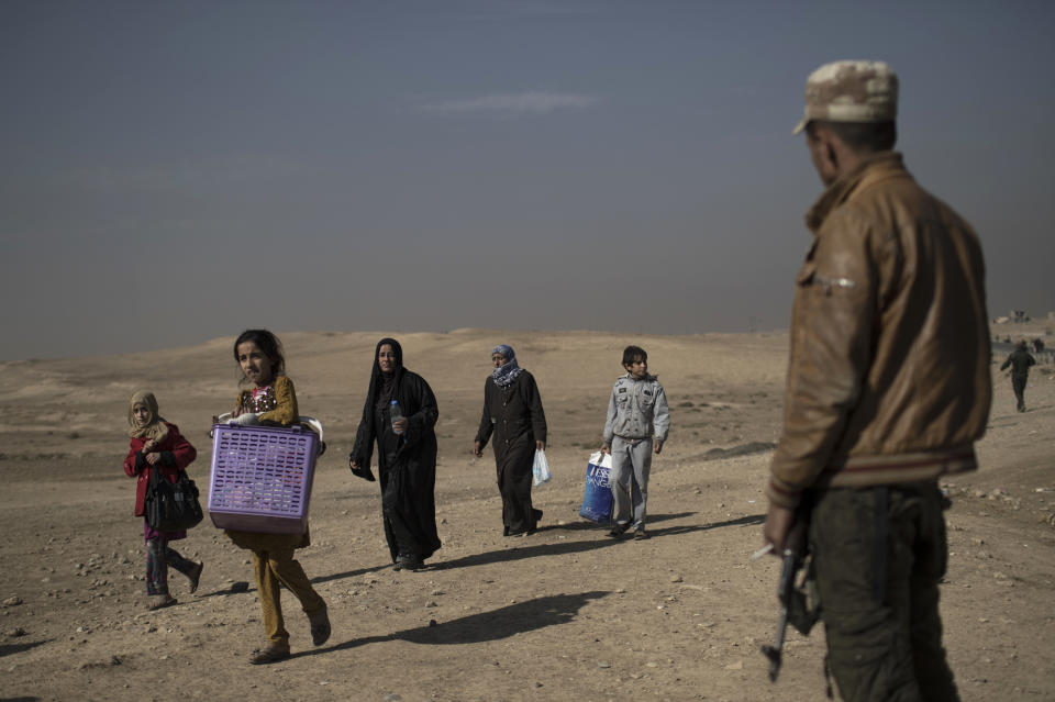 FILE - In this Nov. 6, 2016 file photo, displaced people leave their homes during fighting in Hamam al-Alil, south of Mosul, Iraq. In a report released Wednesday, March 6, 2019, Human Rights Watch said Iraqi and Kurdistan Regional Government authorities have charged hundreds of children with terrorism for alleged affiliation with the Islamic State group, often using torture to coerce confessions. The report said children recruited by armed groups should be recognized primarily as victims who should be rehabilitated and reintegrated into society. (AP Photo/Felipe Dana)