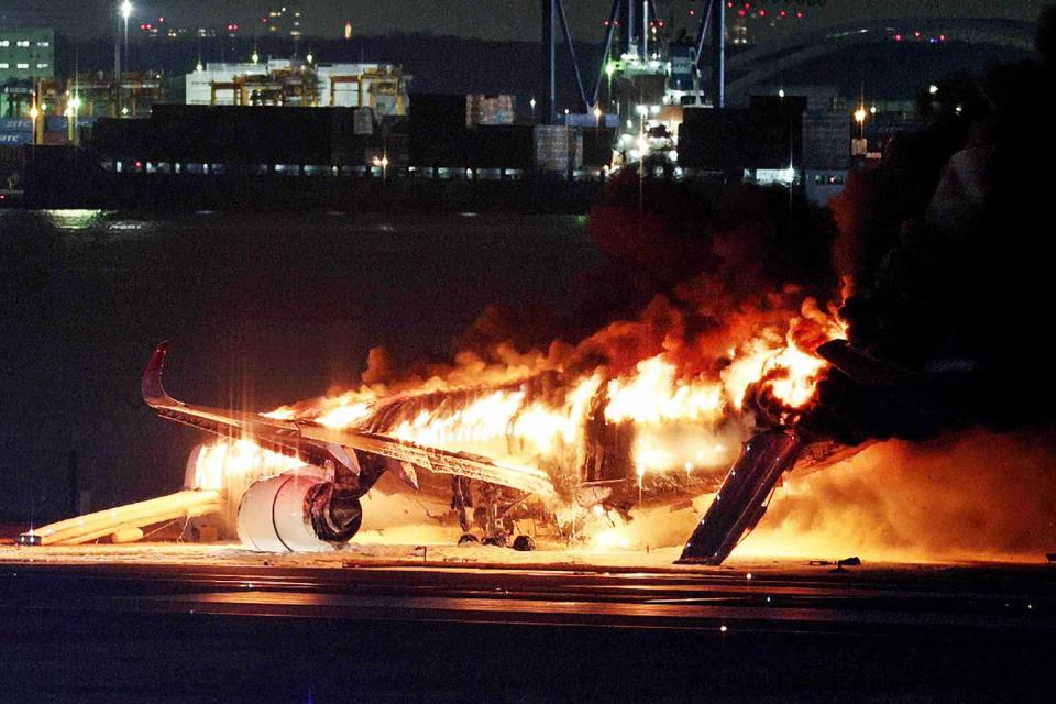 <p>STR/JIJI PRESS/AFP via Getty Images</p> Japan Airlines plane on fire on a runway of Tokyo