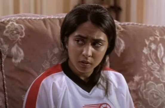 An Indian girl sits on the couch in her soccer uniform