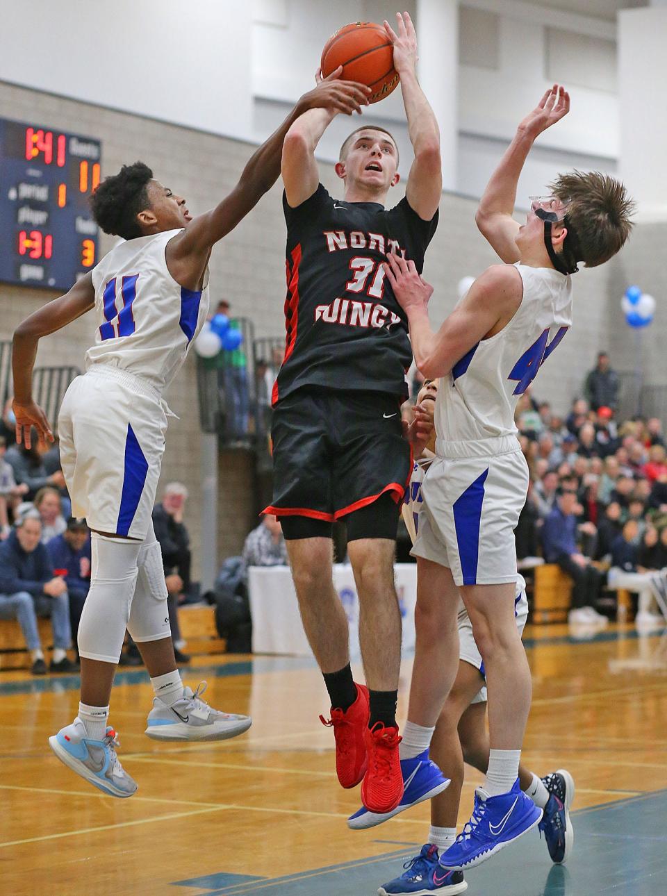 North Quincy captain Zach Taylor takes a jumper between Quincy's Danny Adams, left, and Charlie Coffey. 
Quincy High hosted North Quincy High in basketball. Both girls and boys teams played on Friday January 20, 2023.