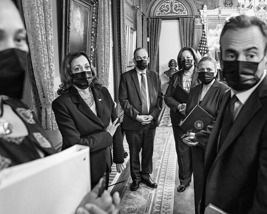 A black and white photo of Kamala Harris with staff in her ceremonial office.