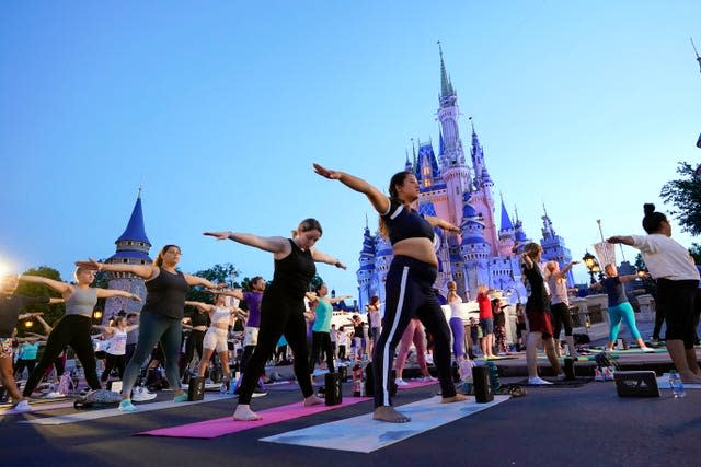 Nearly 2,000 Cast Members practise sunrise yoga celebrating International Yoga Day in front of Cinderella Castle at the Magic Kingdom Park at Walt Disney World in Lake Buena Vista, Florida