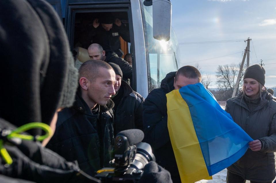 Dozens of Ukrainian PoWs, wearing black Russian prisoner uniforms, leave a bus as part of the swap (via REUTERS)