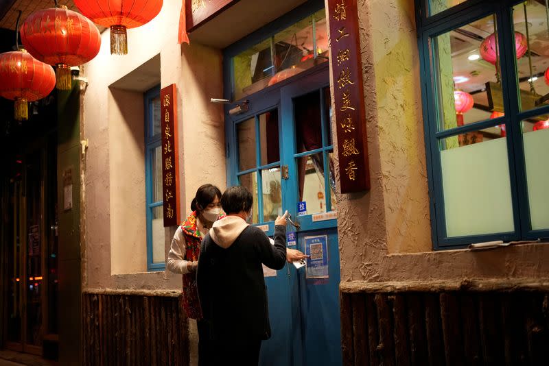 A waiter guides a customer to scan a health QR code outside a restaurant as coronavirus disease (COVID-19) outbreaks continue in Shanghai