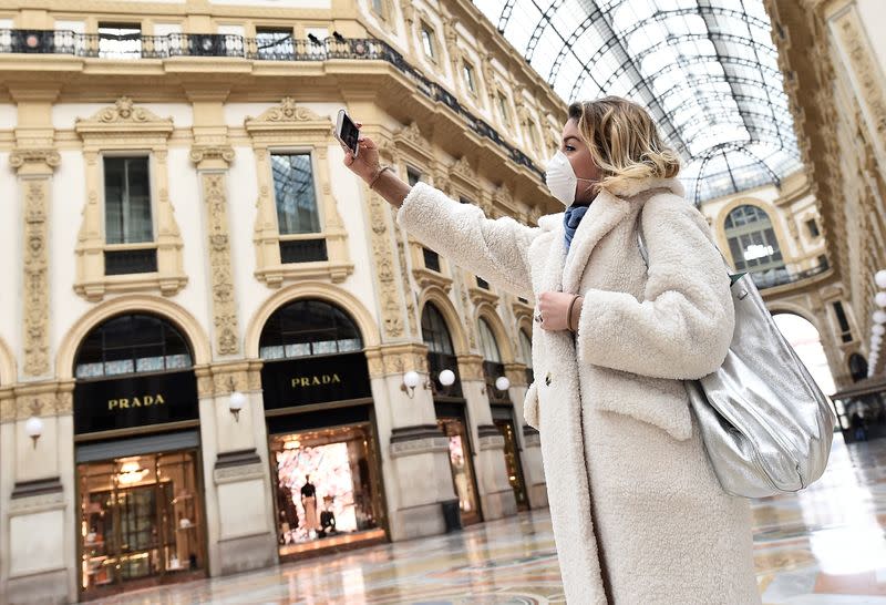 A woman wearing a protective face mask takes a selfie in Galleria Vittorio Emanuele II after a decree orders for the whole of Italy to be on lockdown in an unprecedented clampdown aimed at beating the coronavirus, in Milan