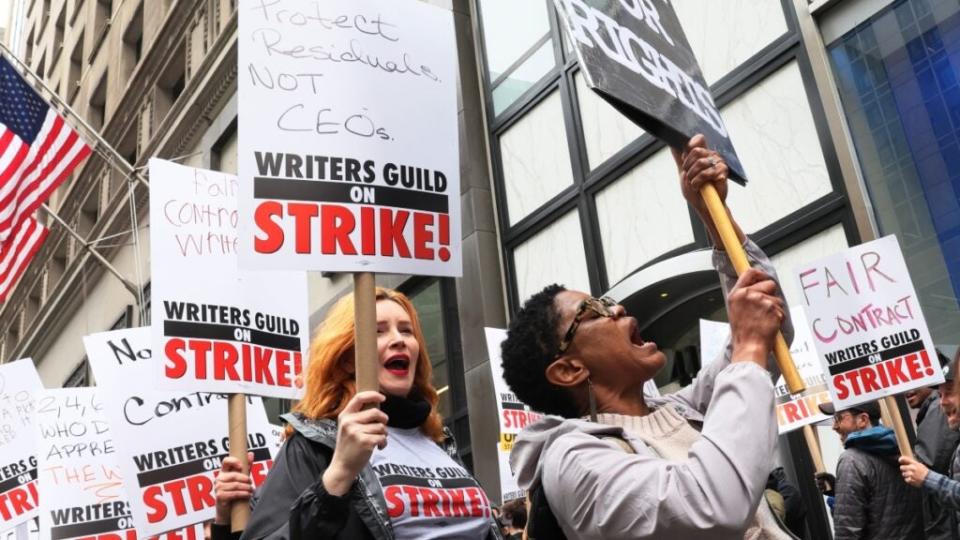 Members of the Writers Guild of America (WGA) East hold signs as they walk on the picket-line outside of the Peacock NewFront on May 02, 2023 in New York City.