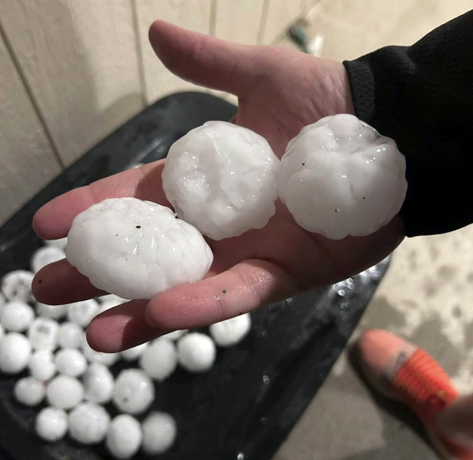 In this image provided by Jeremy Crabtree, large chunks of hail are shown, Wednesday night, March 13, 2024, in Shawnee, Kan. Volatile weather was honing in on parts of Kansas and Missouri Wednesday night, with some storms bringing massive chunks of hail. (Jeremy Crabtree via AP)