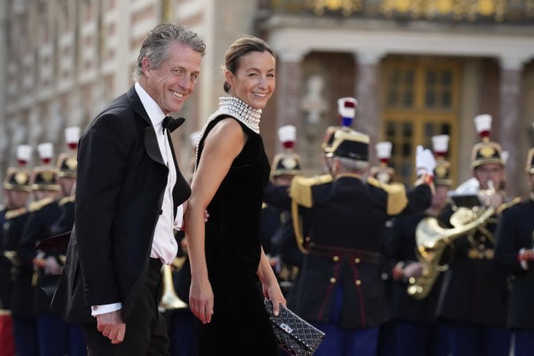 Hugh Grant y Anna Elisabet Eberstein llegan a una cena de Estado celebrada en honor del rey Carlos III y la reina Camila, en el Palacio de Versalles, al oeste de París, el miércoles 20 de septiembre de 2023.  (AP/Christophe Ena)