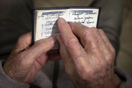 90 year old Holocaust survivor Hy Abrams points at the word "Auschwitz" as he poses for a photo with a book that he carries with him everyday that documents all the different concentration camps he was held in during the second World War, in the Brooklyn borough of New York January 15, 2015. REUTERS/Carlo Allegri