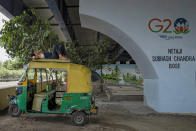 An auto rickshaw driver sleeps on the roof of his rickshaw under an elevated road next to a G20 logo in New Delhi, India, Thursday, Sept., 7, 2023. Leaders of the Group of 20 leading rich and developing countries are gathering in New Delhi this weekend for their annual summit. (AP Photo/Altaf Qadri)