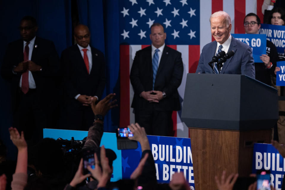 President Biden, smiling broadly, speaks at a Democratic National Committee rally.