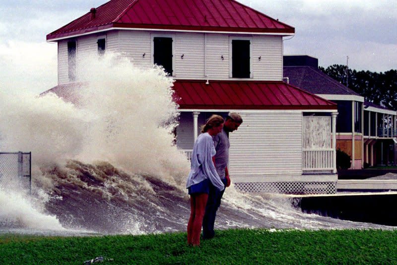 Stephanie Kearny and Jamison Stubbs watch as the rising waters of Lake Pontchartrain crash into the Coast Guard Station at New Orleans, in the background, as Hurricane Georges makes its way toward the Gulf coasts September 27, 1998. On September 21, the storm began its rampage in the Caribbean. File Photo by A.J. Sisco/UPI