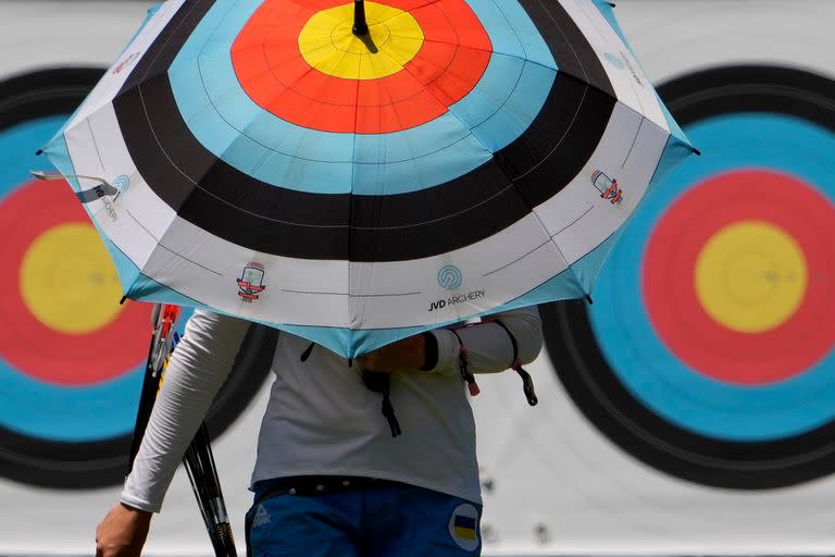 No parece una buena decisión el uso de esa sombrilla por parte de un atleta ucraniano mientras se aleja de los blancos de arquería durante una practica.