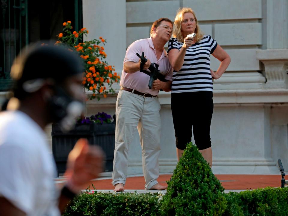 FILE - In this June 28, 2020 file photo, armed homeowners Mark and Patricia McCloskey, standing in front their house along Portland Place confront protesters marching to St. Louis Mayor Lyda Krewson's house in the Central West End of St. Louis. Authorities executed a search warrant Friday evening, July 10, 2020, at the St. Louis mansion owned by the McCloskey's, a white couple whose armed defense of their home during a racial injustice protest last month made national headlines. said. Joel Schwartz, who is now representing the couple, confirmed on Saturday that a search warrant was served, and that the gun Mark McCloskey was seen holding during last month's protest was seized.  (Laurie Skrivan/St. Louis Post-Dispatch via AP)