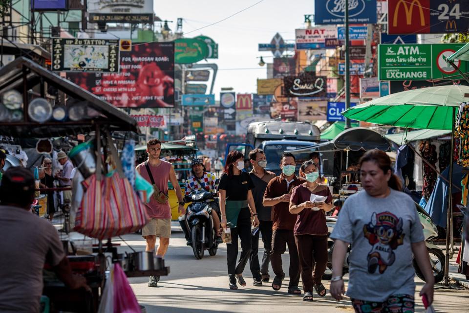 People wear facemasks While walking along Khao San Road, a popular area for tourists in Bangkok