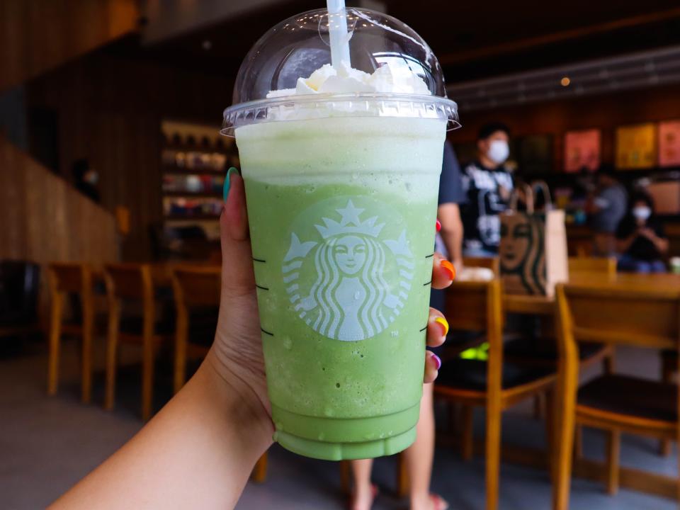 hand holiding matcha green tea frappuchino at starbucks