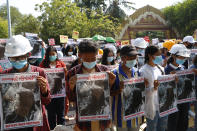 Mandalay University graduates bow their heads as they hold posters with an image of Mya Thwate Thwate Khaing, a 19-year old woman shot by police on Feb. 9 in Naypyitaw, during an anti-coup protest in Mandalay, Myanmar, Sunday, Feb. 14, 2021. Daily mass street demonstrations in Myanmar are on their second week, with neither protesters nor the military government they seek to unseat showing any signs of backing down from confrontations. (AP Photo)