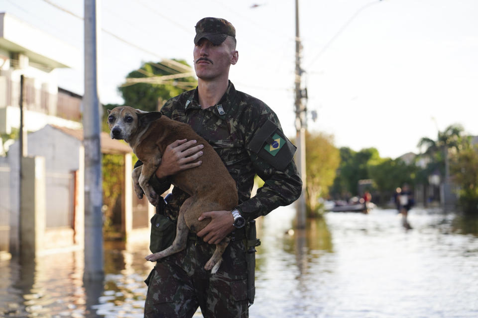 A soldier evacuates a dog from a flooded area after heavy rain in Canoas, Rio Grande do Sul state, Brazil, Thursday, May 9, 2024. (AP Photo/Carlos Macedo)