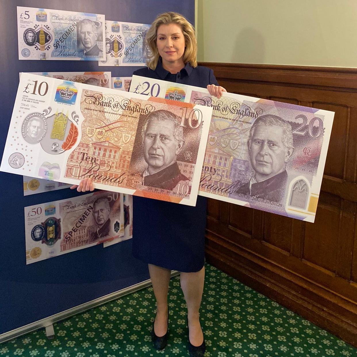 Ms Mordaunt holds up some outsized posters of the £10 and £20 notes