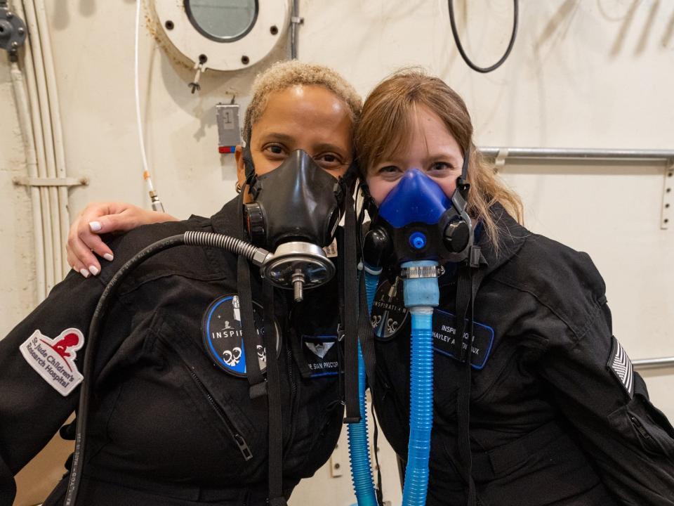 inspiration4 crew members sian proctor and hayley arceneaux wearing gas masks in altitude chamber