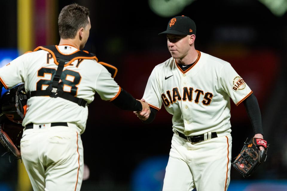Anthony DeSclafani celebrates with catcher Buster Posey after pitching a shutout against the Rockies.