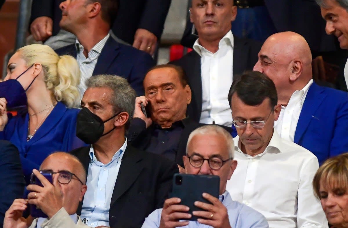 Berlusconi is flanked by Adriano Galliani, partially seen at right, as he talks on his phone during a Serie A football match between Monza and Torino in 2022 (LaPresse)