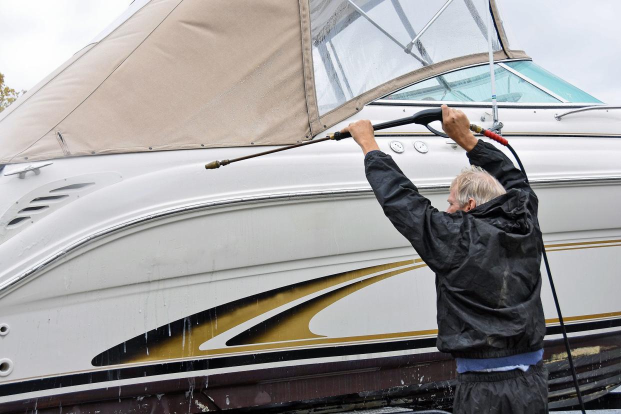 Caucasian man cleaning a power boat with pressure washer