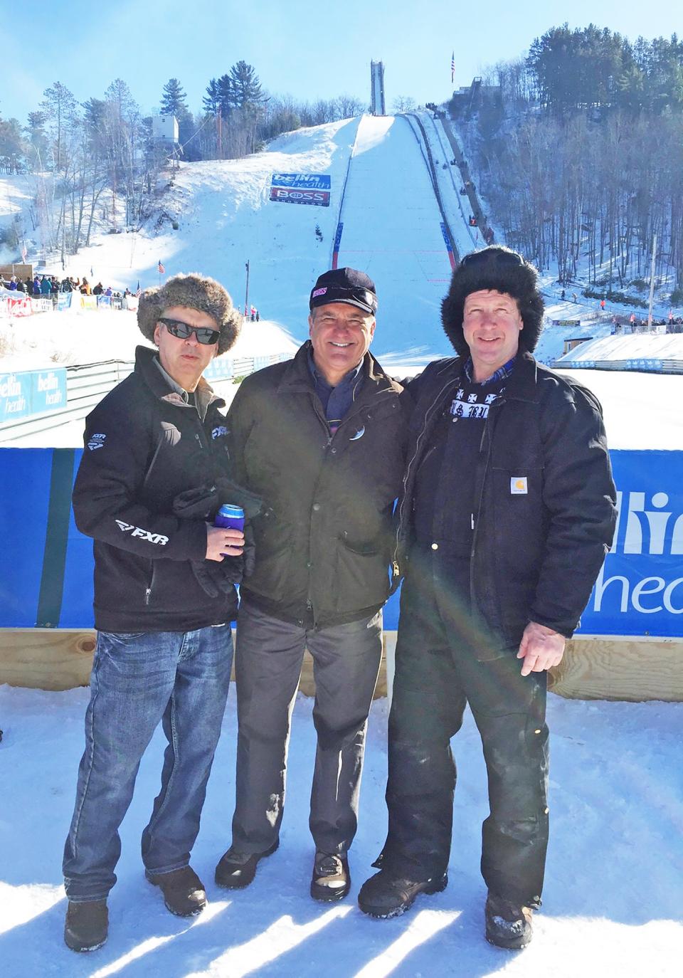 Ron Niemela of Vulcan, Michigan, left, and Jeff Minerley of West Allis, Wisconsin, right, have their picture taken with former NFL coach Steve Mariucci during a ski jumping meet at Pine Mountain in Iron Mountain, Michigan.