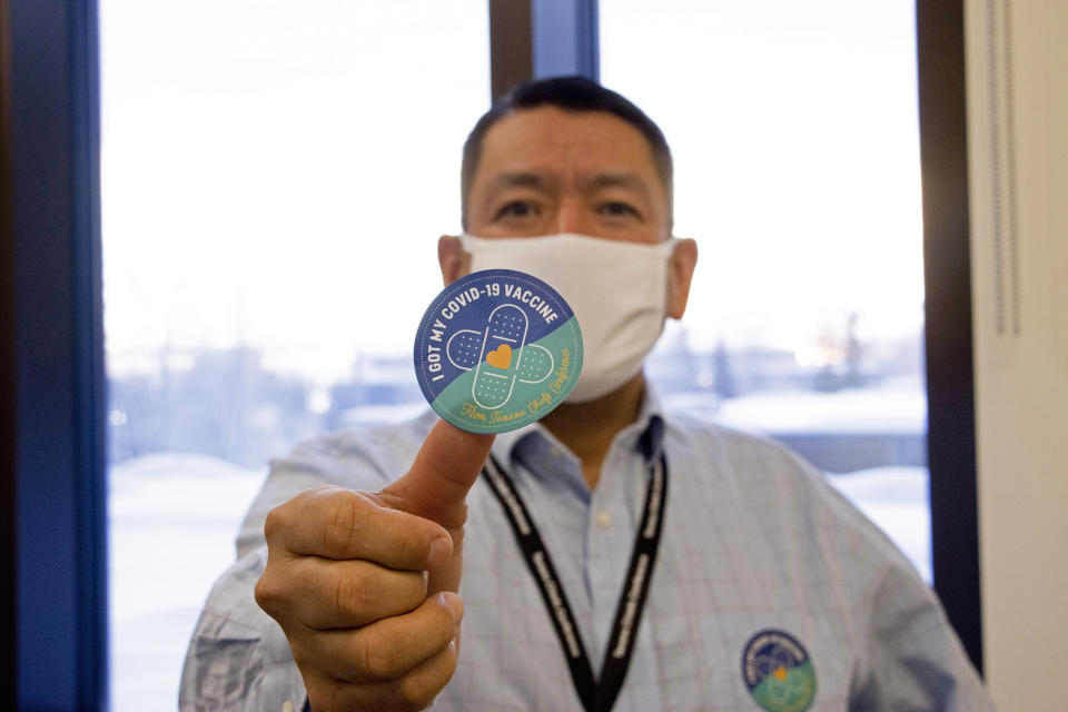 In this undated photo provided by the Tanana Chiefs Conference, shows PJ Simon, chief and chairman of the conference, from Fairbanks, Alaska, displaying a COVID-19 vaccination sticker. Alaska has been one of the leading states in the percentage of its population to be vaccinated against COVID-19. But some of Alaska's highest vaccination rates have been in some of its most remote, hardest-to-access communities, where the toll of past flu or tuberculosis outbreaks hasn't been forgotten. (Rachel Saylor/Tanana Chiefs Conference via AP)