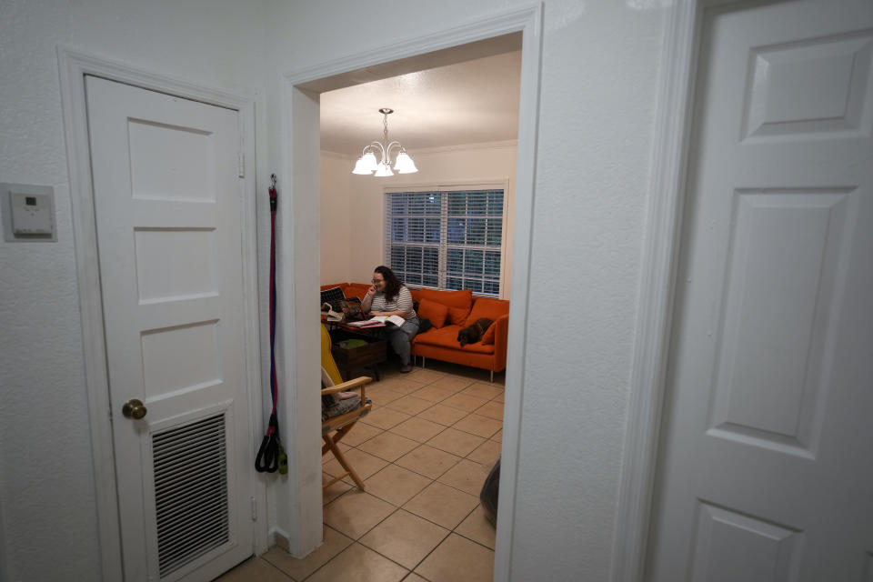 Krystal Guerra, 32, does coursework for a degree program in digital marketing, inside the apartment which she is packing up to leave after her new landlord gave her less than a month's notice that her rent would go up by 26%, Saturday, Feb. 12, 2022, in the Coral Way neighborhood of Miami. Guerra, who works in marketing while also pursuing a degree part-time, had already been spending nearly 50% of her monthly income on rent prior to the increase. Unable to afford a comparable apartment in the area as rents throughout the city have risen dramatically, Guerra is putting many of her belongings into storage and moving in with her boyfriend and his daughter for the time being. (AP Photo/Rebecca Blackwell)