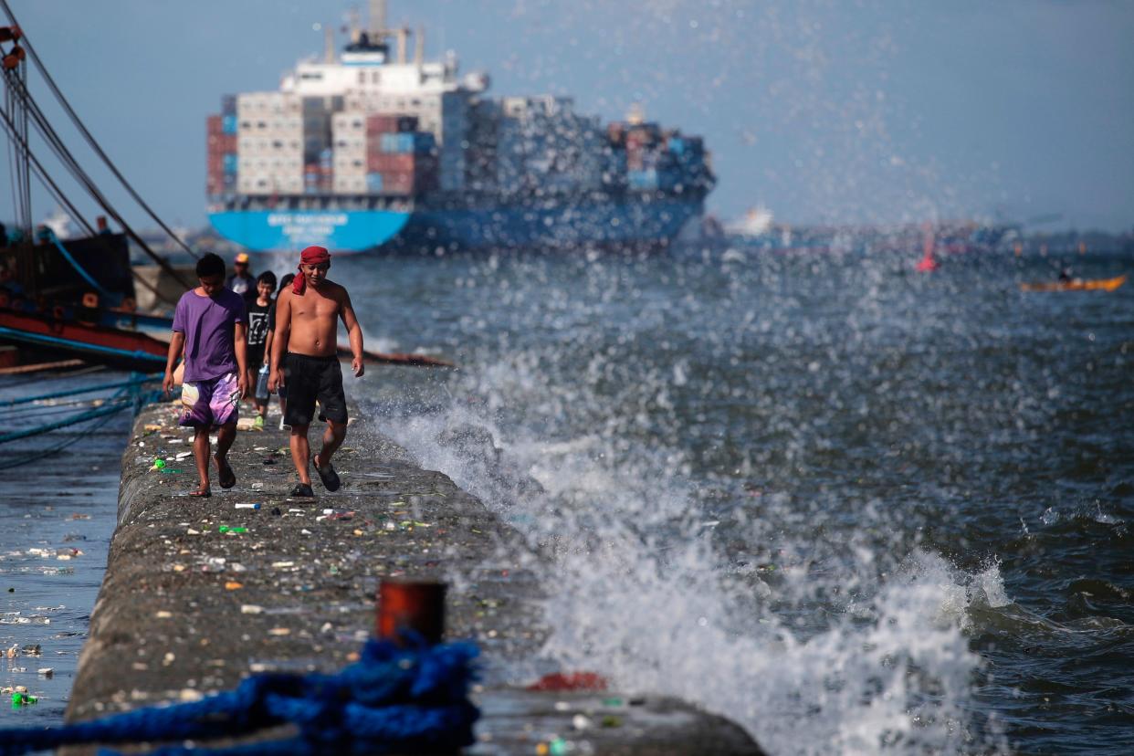 Filipino fishermen maneuver on a breakwater dike in Manila as Typhoon Mawar elicits warnings in the Philippines (EPA)