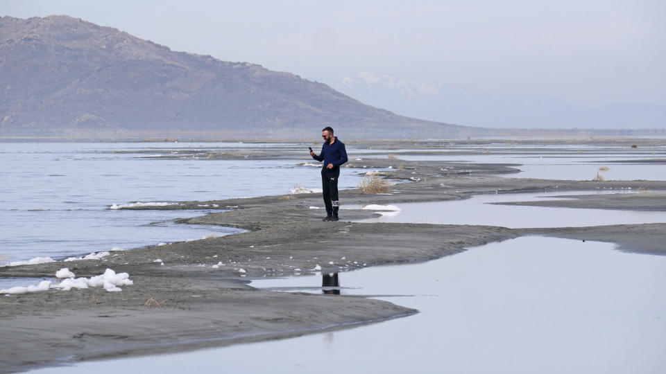 Ruben Gyoeltsyan walks across a sand bar at the receding edge of the Great Salt Lake, Thursday, March 3, 2022, near Salt Lake City. Utah lawmakers passed a $40 million proposal through the state Senate that would pay water rights holders to conserve and fund habitat restoration to prevent the lake from shrinking further. (AP Photo/Rick Bowmer)