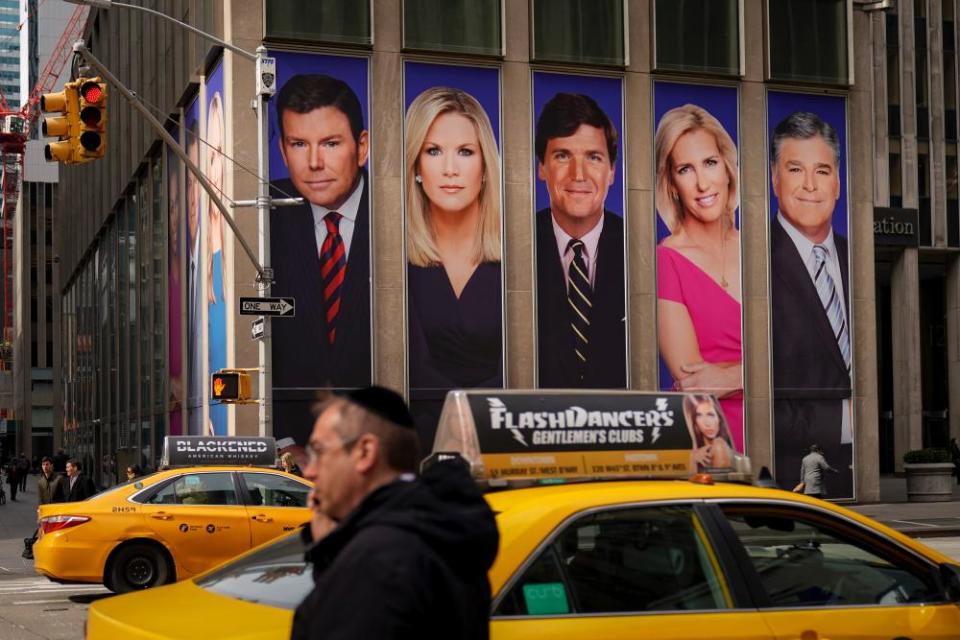 Traffic on Sixth Avenue passes by advertisements featuring Fox News personalities, including Bret Baier, Martha MacCallum, Tucker Carlson, Laura Ingraham, and Sean Hannity, adorn the front of the News Corporation building, March 13, 2019 in New York City.