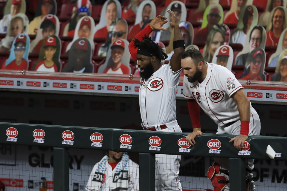 Cincinnati Reds' Brian Goodwin, left, and Curt Casali, right, react to the two-run home run hit by Eugenio Suarez in the sixth inning during a baseball game against the Milwaukee Brewers in Cincinnati, Monday, Sept. 21, 2020. (AP Photo/Aaron Doster)