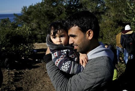A Syrian refugee man holds his baby as he waits on a roadside near a beach in the western Turkish coastal town of Dikili, Turkey, after Turkish Gendarmes prevented them from sailing off for the Greek island of Lesbos by dinghies, March 5, 2016. REUTERS/Umit Bektas
