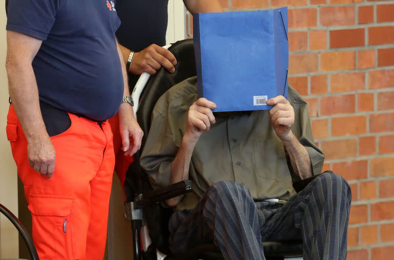 El ex guardia del campo de concentración nazi Josef Schuetz se cubre la cara mientras llega el 28 de junio de 2022 a un gimnasio utilizado como sala de justicia improvisada en Brandenburg an der Havel, este de Alemania, donde se pronunció su veredicto