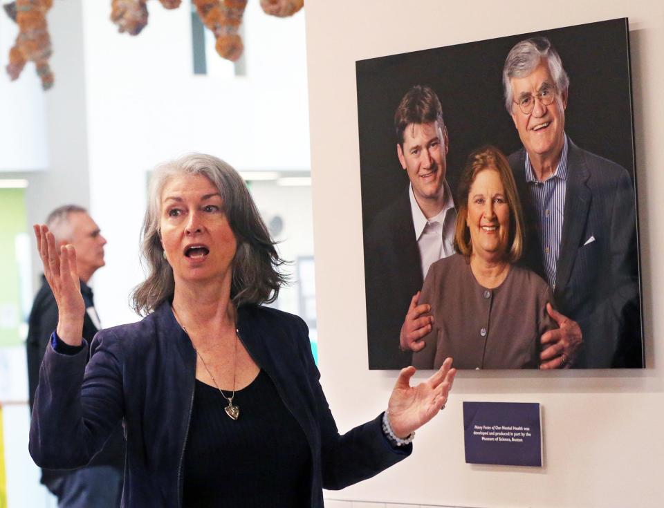 The 99 Faces Project, conceived by artist Lynda Cutrell, addresses issues of stigma and mental illness, is on display at Dover High School. Above, Cutrell discusses an image in the exhibit of former New Hampshire Supreme Court Chief Justice John Broderick, his wife Patti and their son.