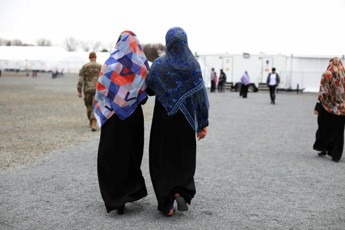 Afghan refugees women and a service member walk inside Liberty Village on Joint Base McGuire-Dix- Lakehurst in Trenton, N.J., Thursday, Dec. 2, 2021. (Barbara Davidson/Pool via AP)