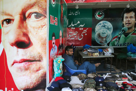 A vendor sits next to images of cricket star-turned-politician Imran Khan, chairman of Pakistan Tehreek-e-Insaf (PTI) at a market in Islamabad, Pakistan, July 27, 2018. REUTERS/Athit Perawongmetha