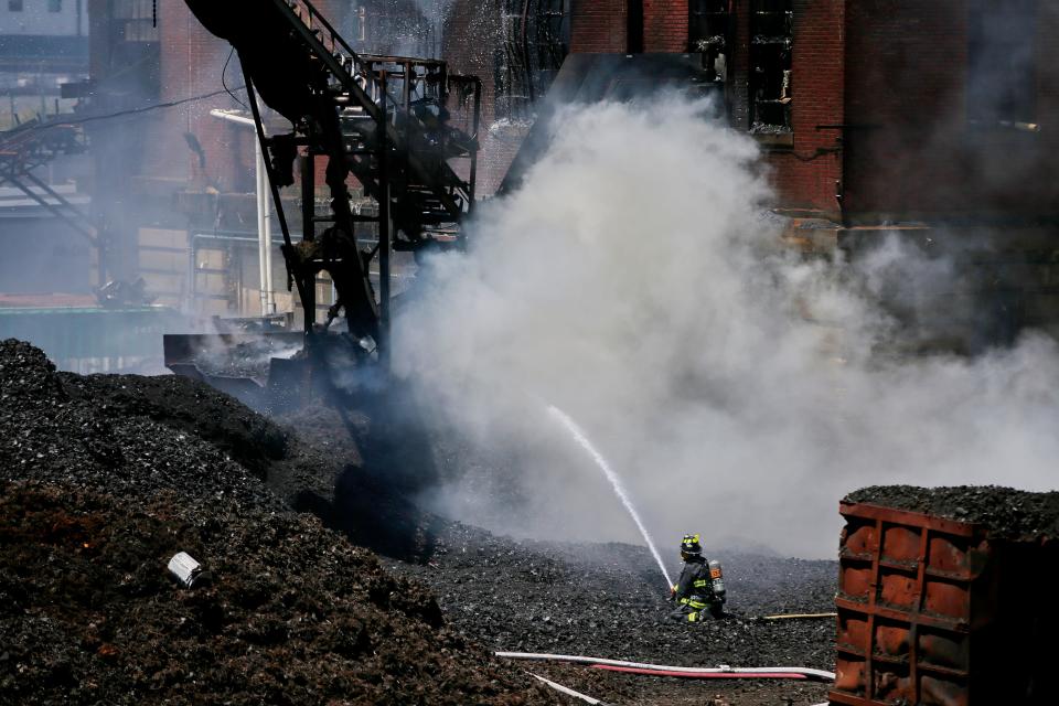 Surrounded by the scrap tires a New Bedford firefighter is seen battling a multi-alarm fire at Bob's Tire Company on Brook Street.
