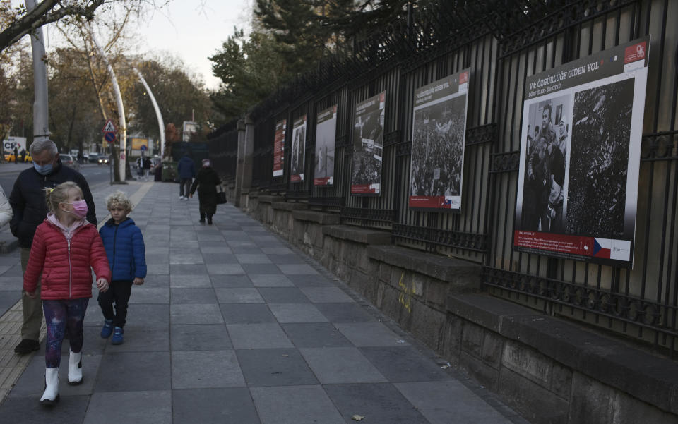 A teenager wearing a mask to help protect against the spread of coronavirus, looks at an open air photo exhibition, in Ankara, Turkey, Monday, Nov. 30, 2020.Turkey's President Recep Tayyip Erdogan has announced Monday the most widespread lockdown so far amid a surge in COVID-19 infections, extending curfews to weeknights and full lockdowns over weekends.(AP Photo/Burhan Ozbilici)