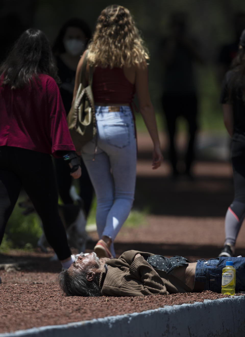 A homeless man sleeps on a sidewalk amid the new coronavirus pandemic on Chapultepec Park in Mexico City, Sunday, July 19, 2020. (AP Photo/Marco Ugarte)