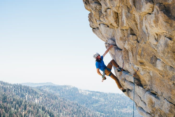 Man rock climbs in a helmet.