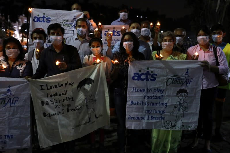 People wearing protective masks hold electric candles as they take part in a campaign to raise awareness about air pollution in Kolkata