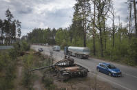 Cars pass by Russian tanks destroyed in a recent battle against Ukrainians in the village of Dmytrivka, close to Kyiv, Ukraine, Monday, May 23, 2022. (AP Photo/Efrem Lukatsky)