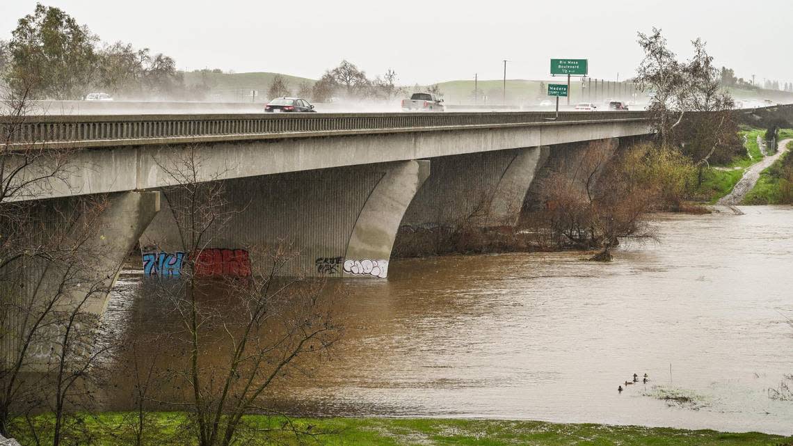 San Joaquin River water swells along the Highway 41 bridge between Fresno and Madera counties as rain continues during an atmospheric river event on Saturday, Jan. 14, 2023.