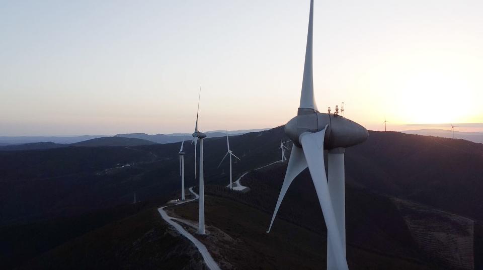 Wind turbines at a wind farm in Portugal with a sunset in the background.